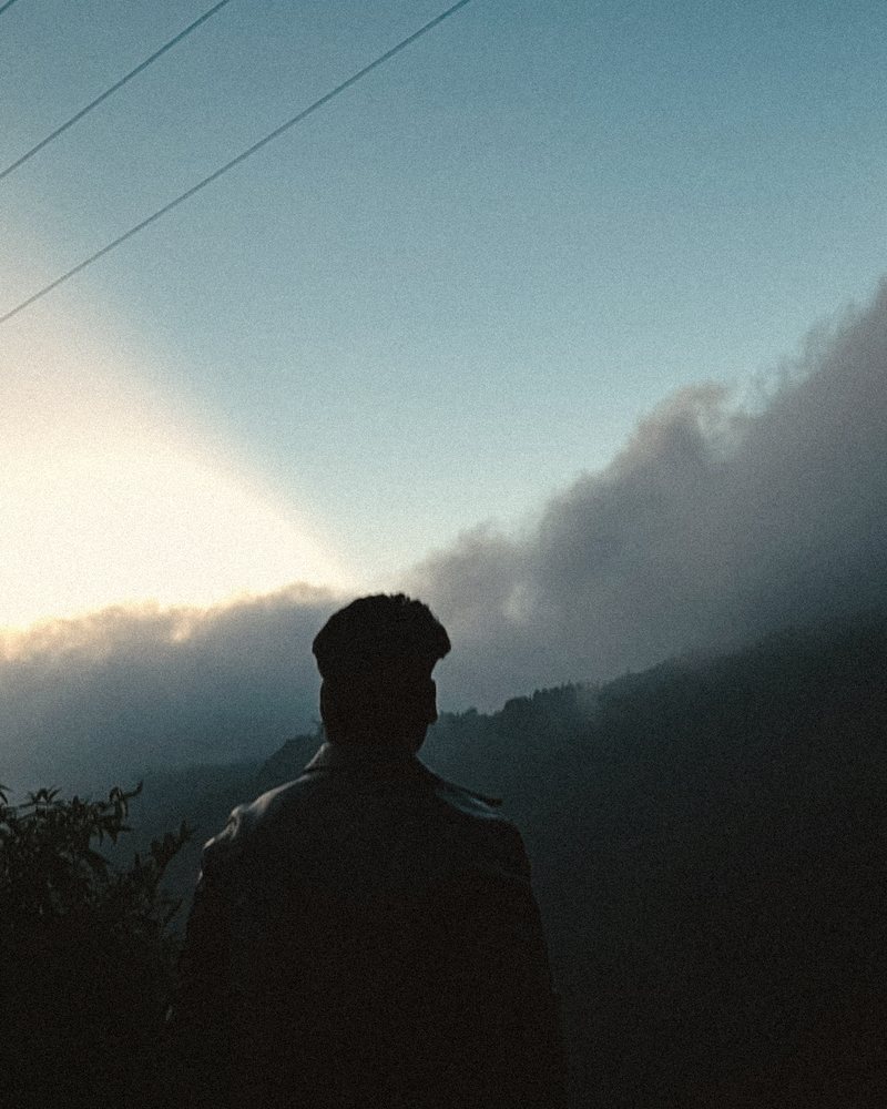 Faraz silhouetted against a misty mountain sunrise